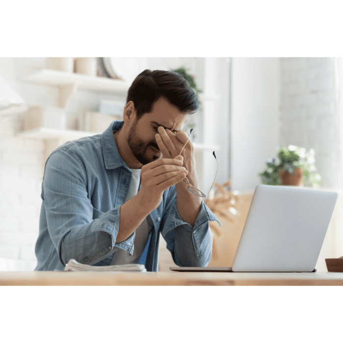 Man rubbing his eyes at a computer.